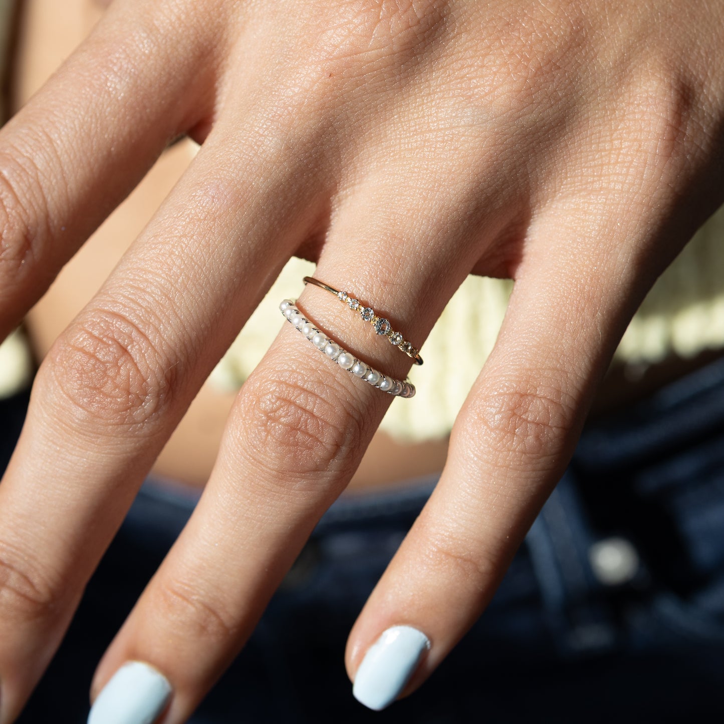 Close-up of a hand wearing multiple diamond rings with a blurred background