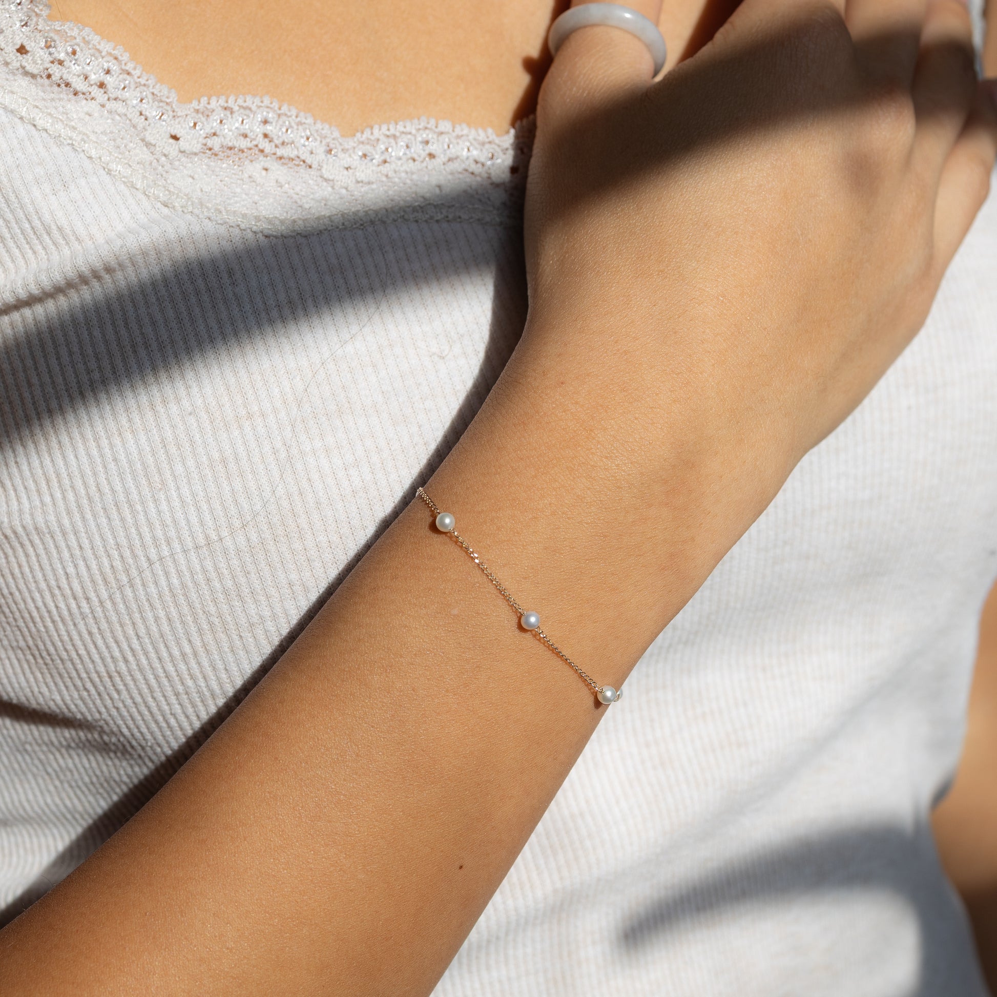 Close-up of a wrist wearing a delicate bracelet with small beads on a light background