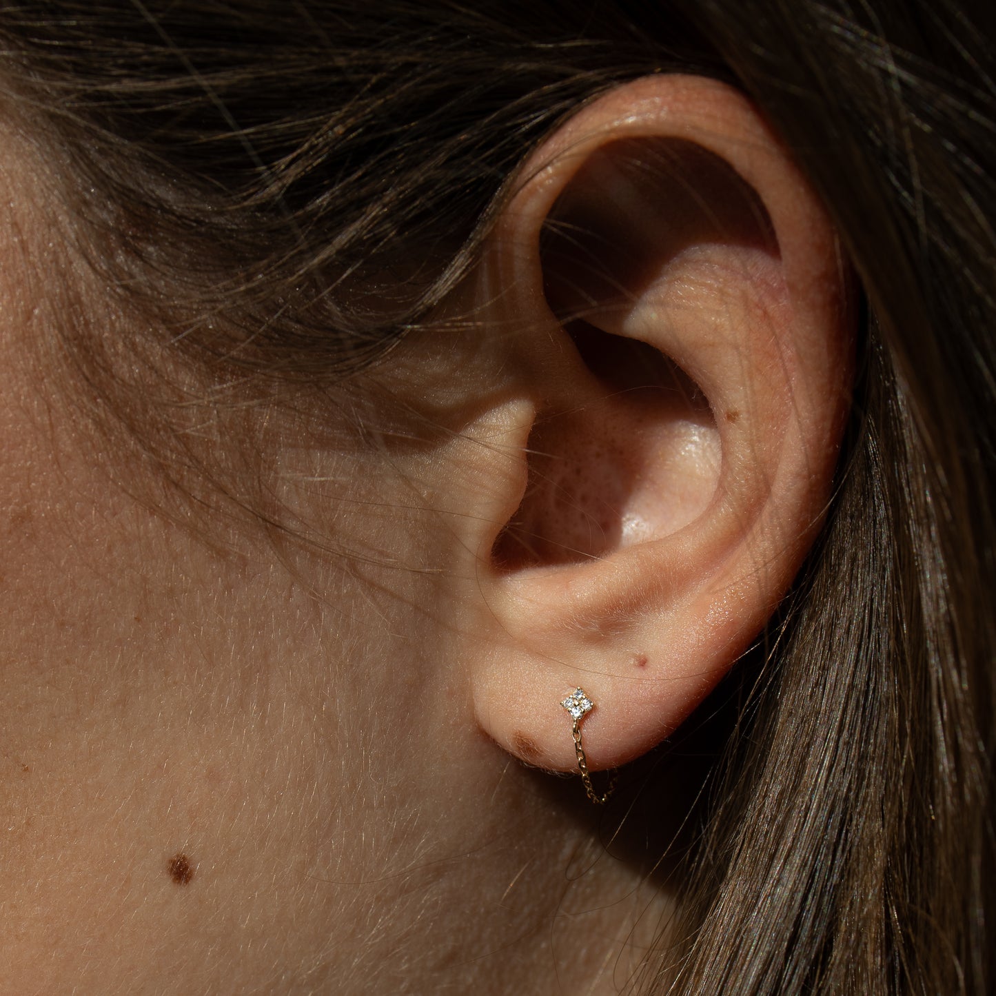 Close-up of an ear with a diamond stud earring.