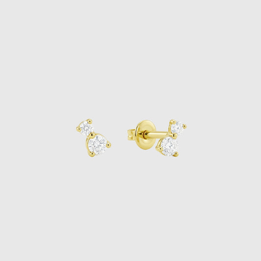 Pair of gold stud earrings with clear gemstones on a light gray background