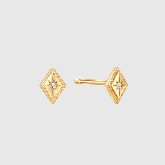 Gold diamond-shaped earrings with central gemstones on a light gray background