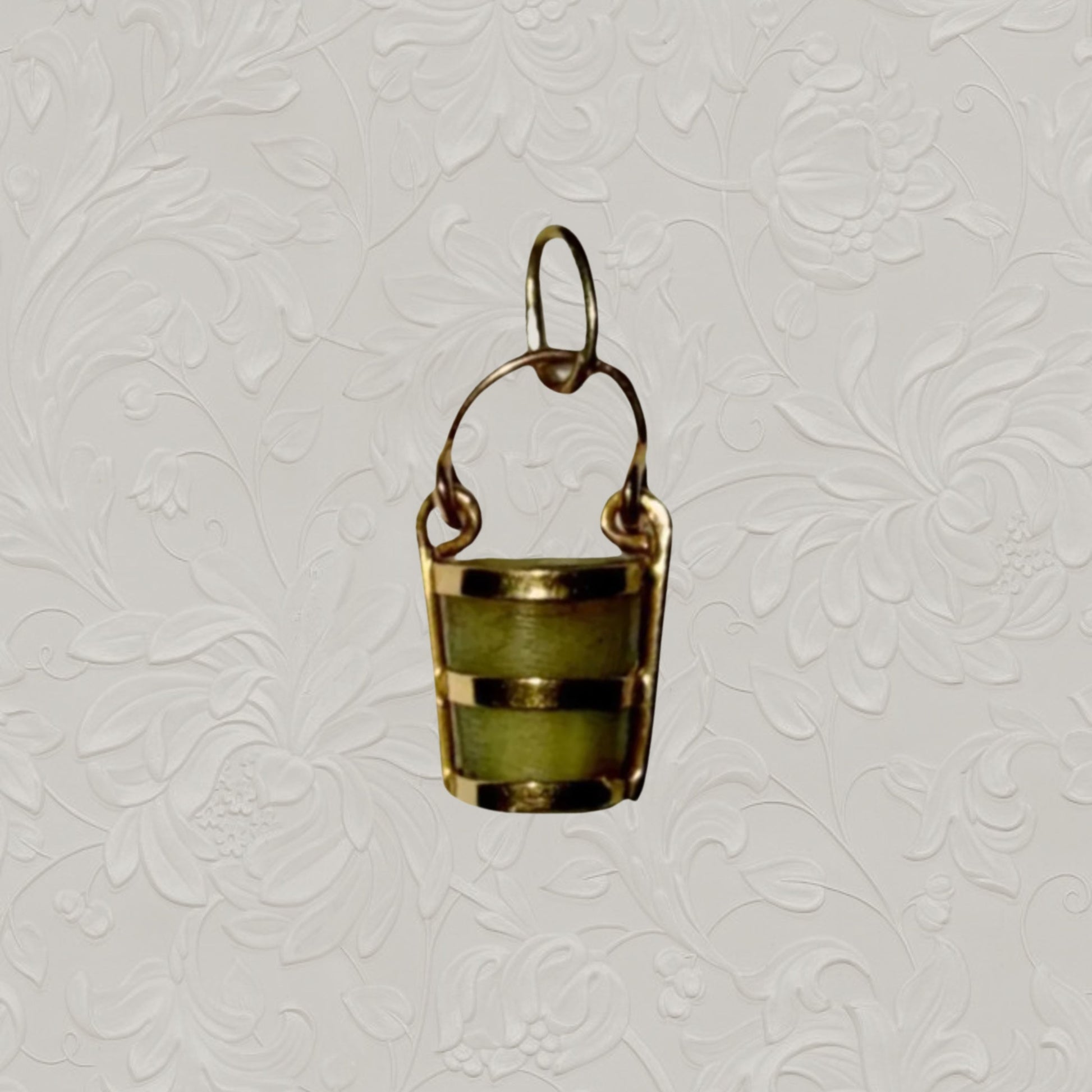 Small green stone pendant with gold accents on a textured gray background