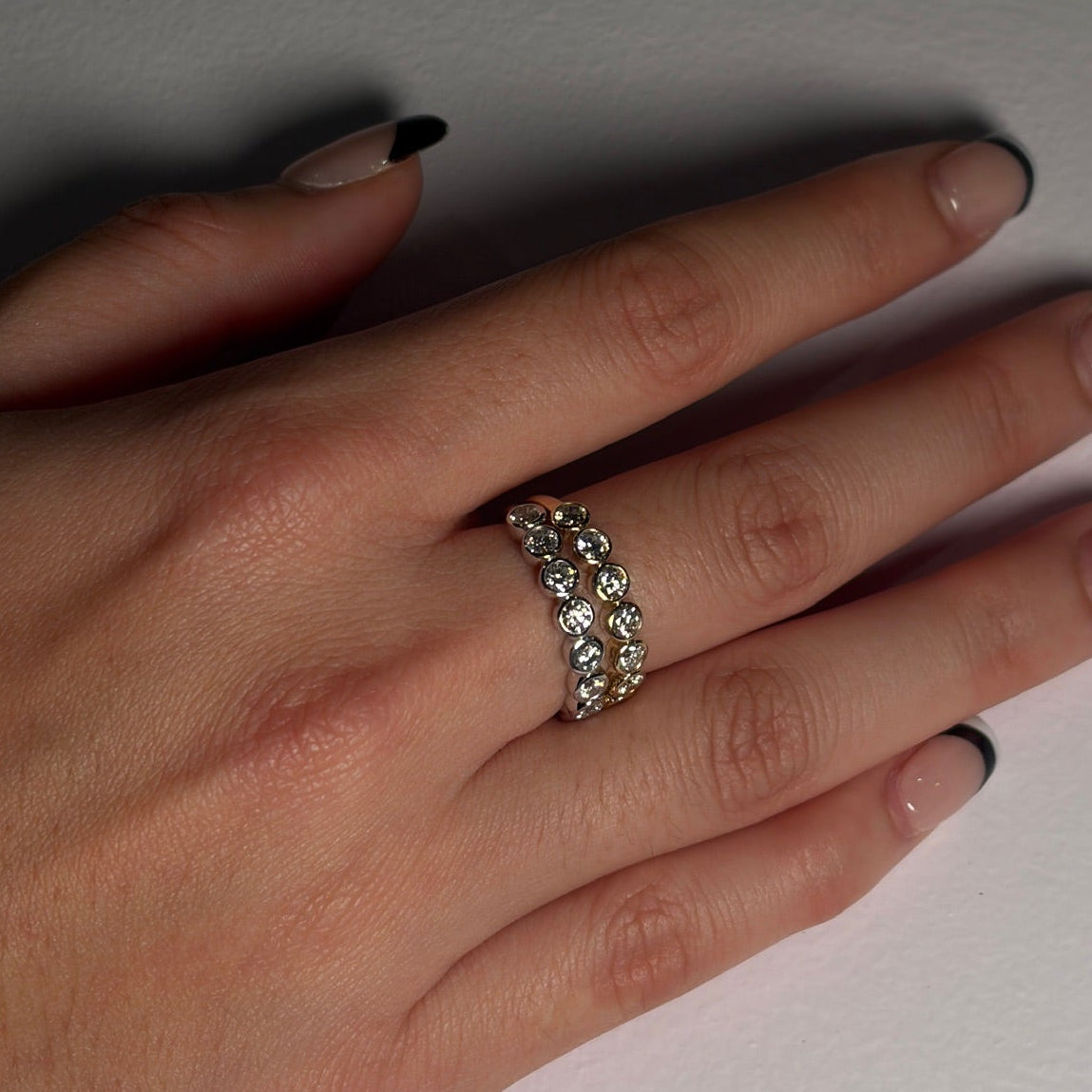 Hand wearing a ring with gemstones on a plain background